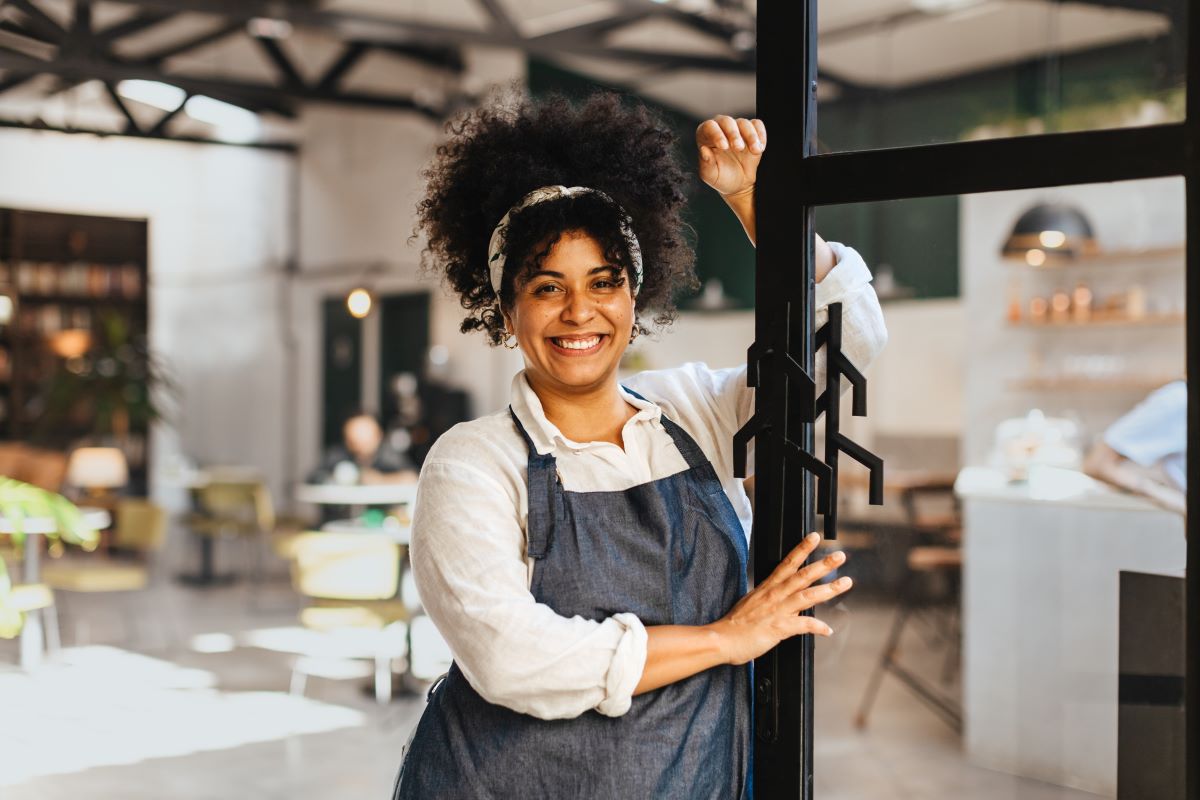 Cafe owner smiling and standing inside her small business