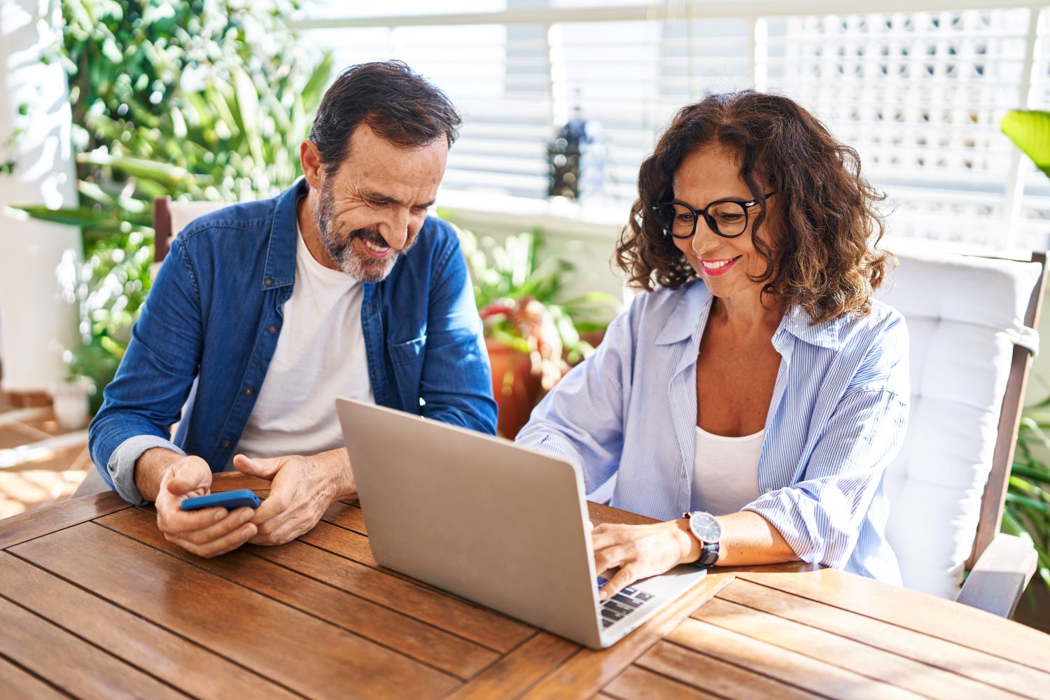 Couple using laptop at their home patio